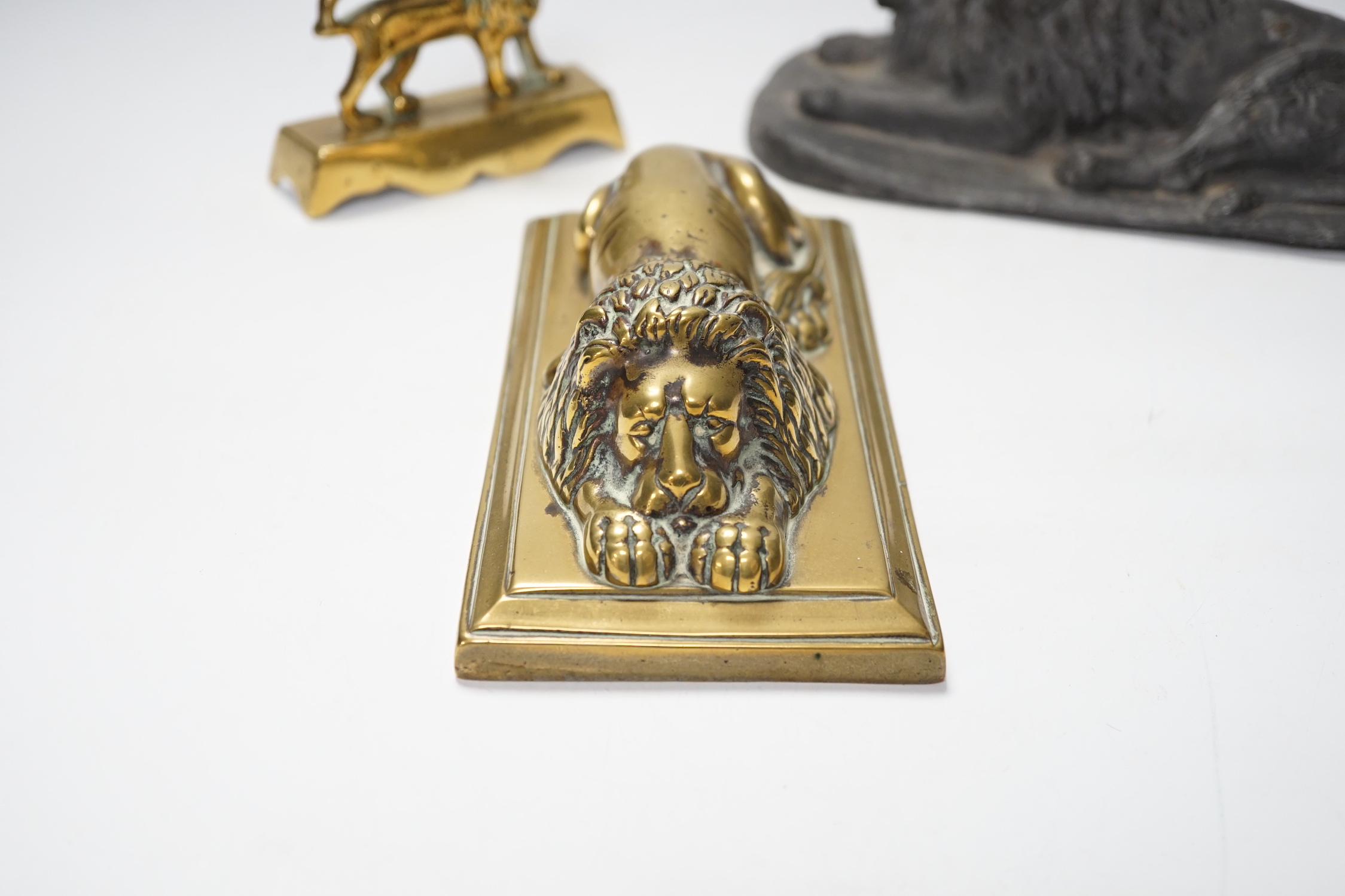 A 19th century brass recumbent lion, a similar cast iron lion and a smaller lion, largest 22cm wide